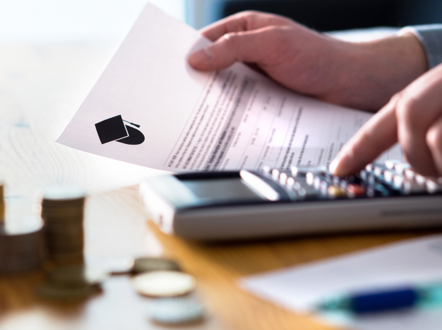 Closeup of hands using a calculator while poring over a financial form